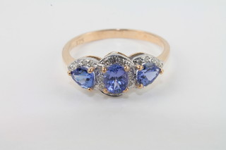 A lady's gold dress ring set 3 oval cut tanzanites supported by diamonds