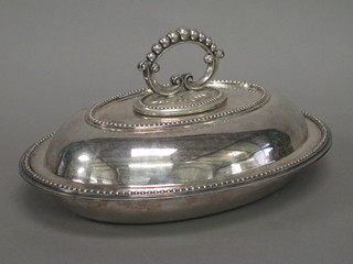 An oval silver plated entree dish and cover with beadwork border
