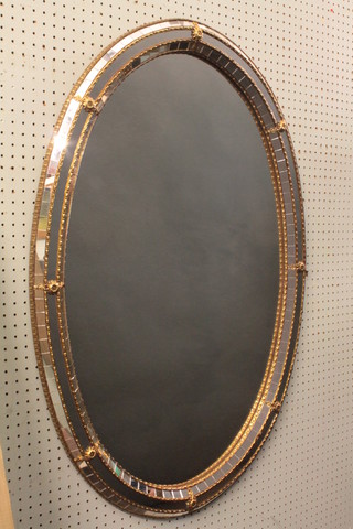 A decorative oval plate wall mirror contained in a gilt metal and  cut glass frame 38"