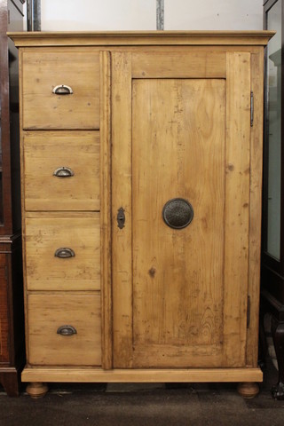 A pine combination cupboard with shelved interior enclosed by a panelled door the base with 4 short drawers, raised on bun feet  38"