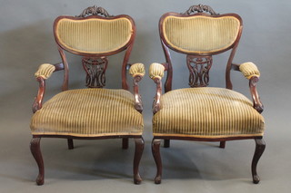 A pair of Edwardian mahogany open arm chairs, upholstered in green material, raised on cabriole supports