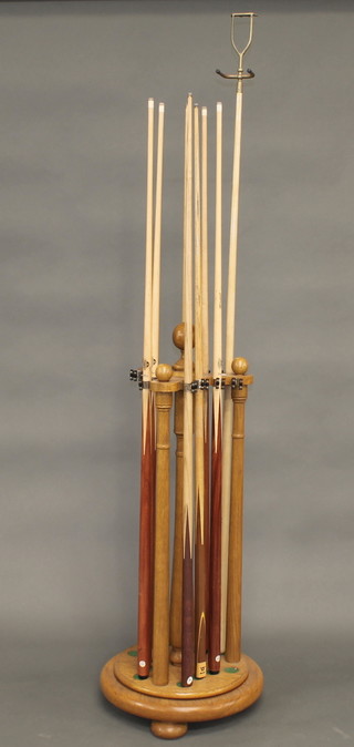 An oak triform shaped snooker rack with 8 cues and a rest