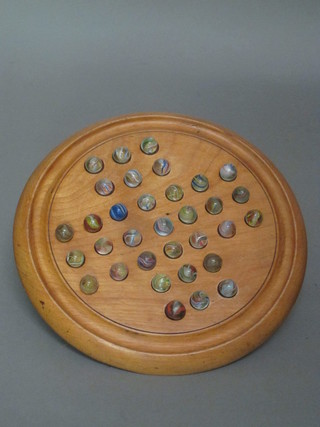 A circular wooden solitaire board complete with marbles
