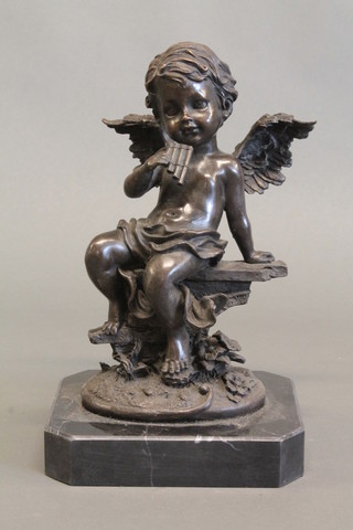 A bronze figure of a seated cherub, raised on a black marble  lozenge base 14"