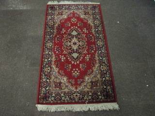 A red ground Persian style machine made rug with central  medallion 62" x 33"