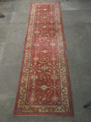 A rust coloured and floral patterned machine made Persian  carpet, some wear, 108" x 26"