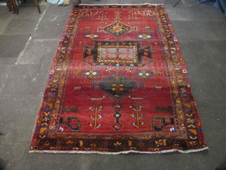 A contemporary red ground Persian rug with geometric design to  the centre 101" x 64"