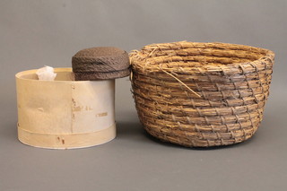 A lady's circular pill box hat by Gaby and a wicker basket