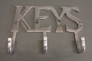 A polished metal 3 hook key rack marked Keys 11"