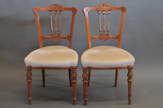 A set of 4 Victorian carved walnut stick and rail back dining  chairs with upholstered seats, raised on turned and fluted supports