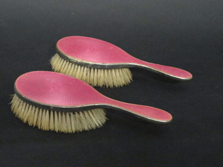 A pair of silver and pink enamel backed hairbrushes