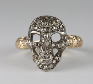 An 18ct yellow gold dress ring in the form of a human skull set diamonds