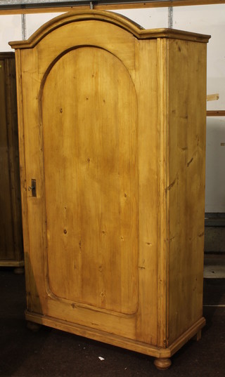 A Continental stripped and polished pine cupboard with arched top and shelved interior enclosed by a panelled door 38"