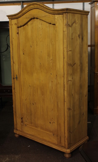 A Continental stripped and polished pine cupboard with domed top, fitted shelves enclosed by a panelled door, raised on bun feet  38"