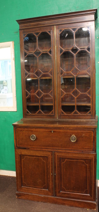 A Georgian mahogany bookcase on cabinet, the upper section  with moulded and dentil cornice, the shelved interior enclosed by  astragal glazed doors, the base fitted 1 long drawer above a  double cupboard, raised on a platform base 36"