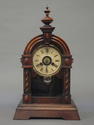 A Continental mantel striking alarm clock with paper dial and Roman numerals contained in an arch shaped walnut case