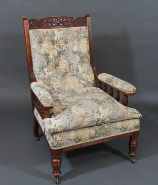 An Edwardian carved walnut show frame armchair with upholstered seat and back, raised on turned supports