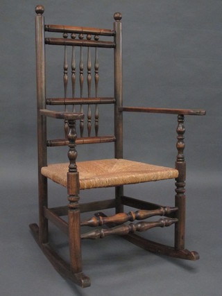 An elm rail back rocking chair with bobbin turned decoration and  woven cane seat