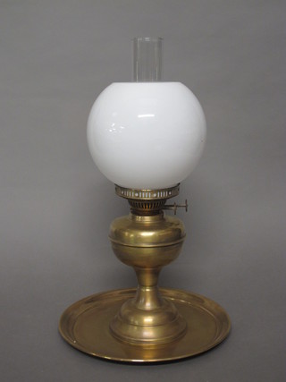 A brass oil lamp with shade and chimney and a brass tray