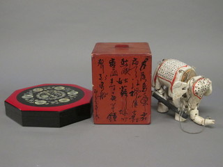 An Oriental red lacquered box 7" and an octagonal lacquered box 11" and a white painted figure of an elephant