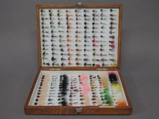 An oak box containing a collection of various fishing flies