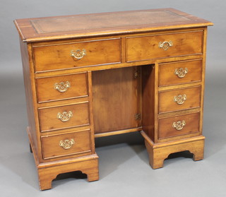 A Georgian style yew kneehole dressing table/desk with inset leather writing surface, fitted 2 long and 6 short drawers, the  kneehole fitted a cupboard enclosed by panelled doors, raised on  bracket feet 36"