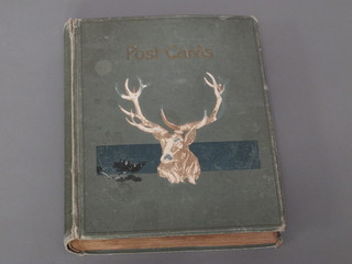 A green album of postcards, cover decorated a stag