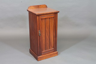 An Edwardian walnut pot cupboard with raised back enclosed by  a panelled door, raised on a platform base 15"
