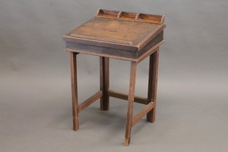 A childs oak writing slope/desk with hinged lid, raised on square tapering supports 19"