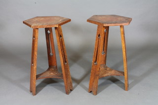 A pair of octagonal oak Art Nouveau 2 tier occasional tables, raised on pierced supports 15"