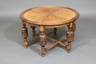 A circular walnut and oak coffee table, raised on 6 baluster  turned supports with X framed stretcher 30"