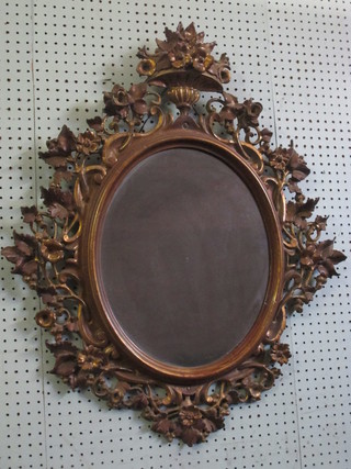 An oval plate wall mirror contained in a decorative gilt frame surmounted by an urn, 32" overall