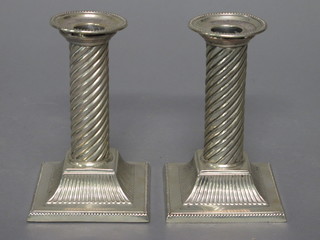 A pair of silver plated candlesticks with spiral decoration and detachable sconces, raised on spreading feet 5"