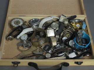 A shallow wooden box containing a collection of wristwatches