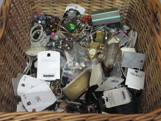 A wicker basket containing a large collection of costume jewellery