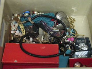 A brown plastic crate containing costume jewellery