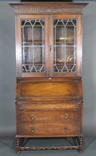 A carved oak bureau bookcase, the upper section with moulded cornice, the shelved interior enclosed by lead glazed panelled  doors, the base fitted a fall front above 2 long drawers, raised on  turned supports 37"