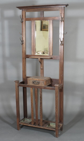 An Art Nouveau oak hall stand, the raised back fitted a  rectangular bevelled plate mirror, the base fitted a glove box with  drawer, complete with trays, 28"