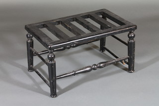 A rectangular ebonised luggage rack raised on turned supports  23"