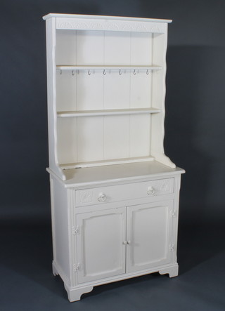 A white painted carved dresser, the raised back fitted 2 shelves,  the base fitted 1 long drawer above a double cupboard, raised on  bracket feet 30"