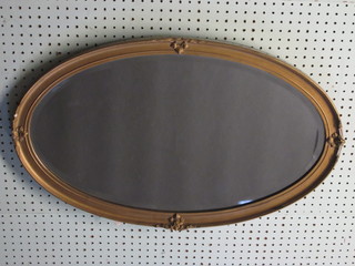 An oval bevelled plate wall mirror contained in a decorative gilt  frame 28"