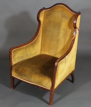 An Edwardian inlaid mahogany winged armchair upholstered in  yellow material, raised on square tapering supports