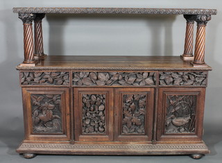A Victorian heavily carved oak buffet with raised top supported  by 4 turned columns with ivy clad capitals, the base fitted 1 long  and 2 short drawers above double cupboards, carved game, raised  on bun feet 67"  ILLUSTRATED