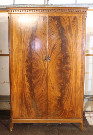 A Georgian style mahogany wardrobe with moulded and dentil cornice, enclosed by panelled doors, raised on bracket feet 49"