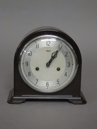 An Art Deco 8 day striking mantel clock with silvered dial and Arabic numerals contained in a brown arched Bakelite case