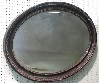 An oval plate wall mirror contained in a decorative frame 24"