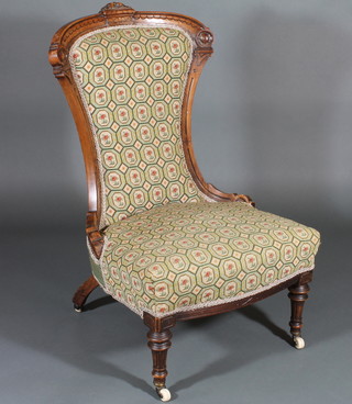 A Victorian carved walnut show frame nursing chair upholstered  in green Berlin tapestry, raised on turned and fluted supports