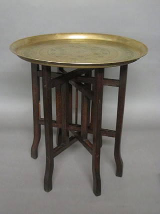 A circular brass tray raised on an oak folding stand 21"