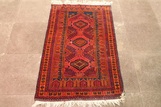 A red ground Persian rug with 3 stylised diamonds to the centre  58" x 36"