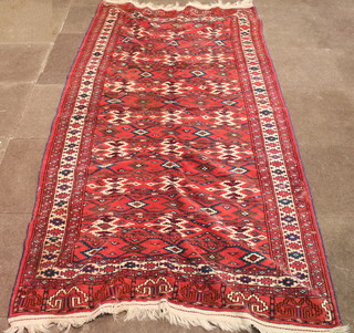 A red ground Bokhara rug with stylised octagons to the centre, misshapen and worn in places 105" x 54"